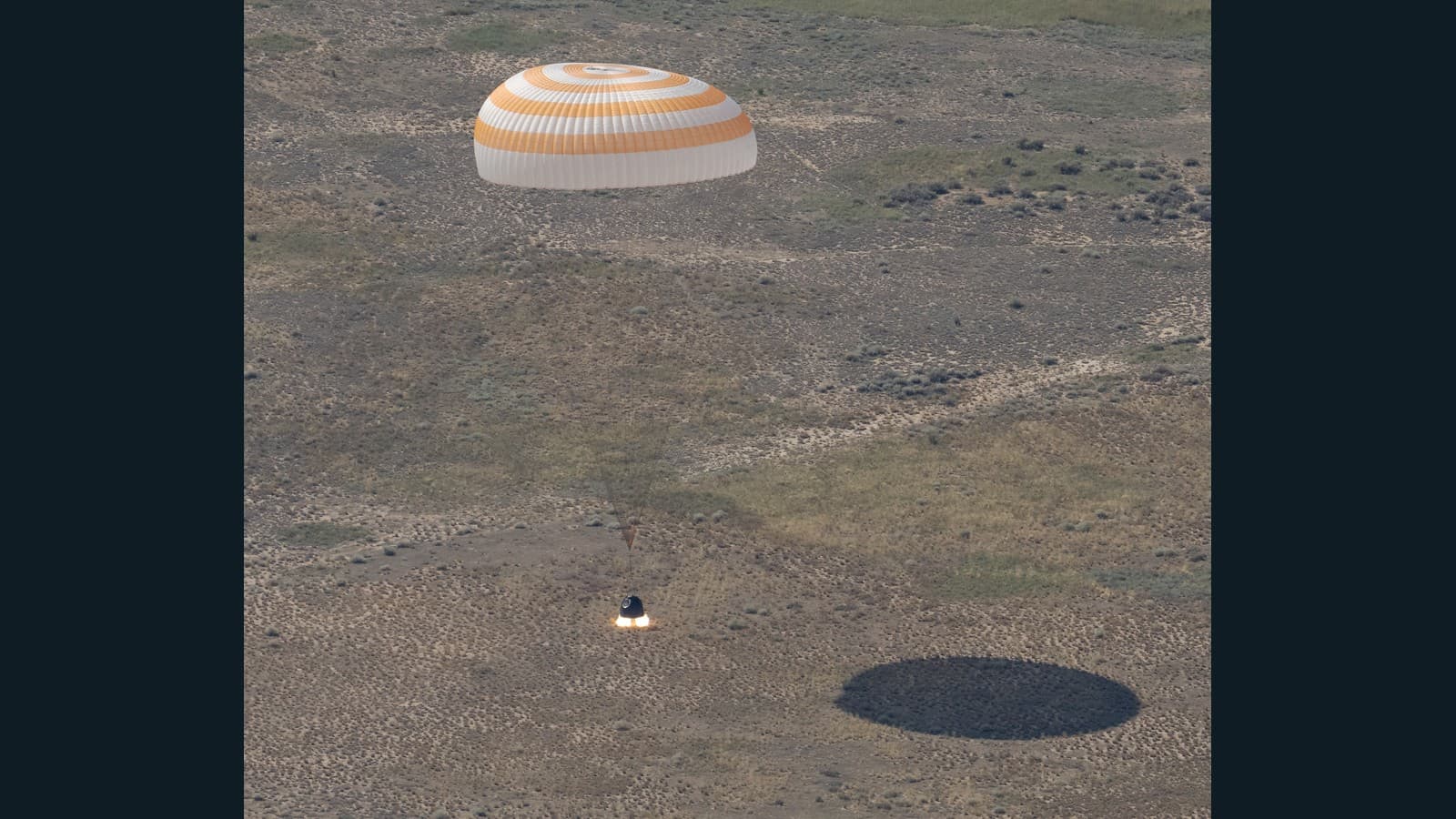 Soyuz MS-28 descends under its orange-and-white parachute toward the Kazakh steppe on July 26, 2026. NASA/Bill Ingalls. Historical mission photograph.