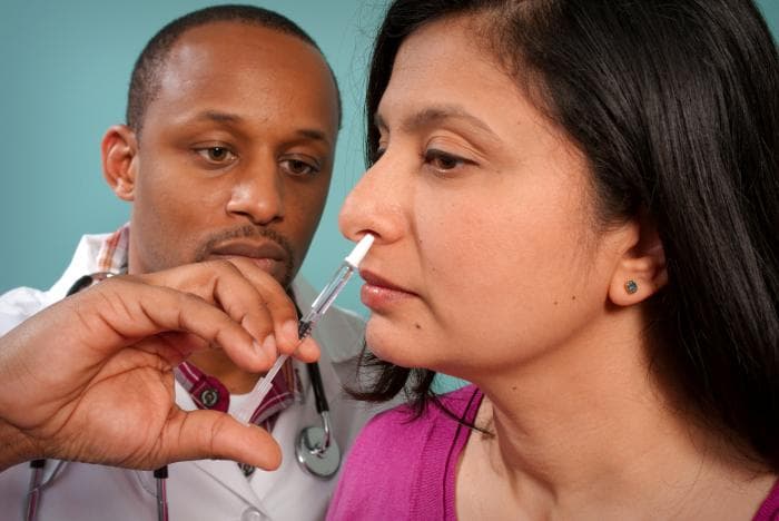 A clinician administers a nasal H1N1 vaccine in a CDC photograph from 2009; historical vaccination context, not a 2026 product recommendation.